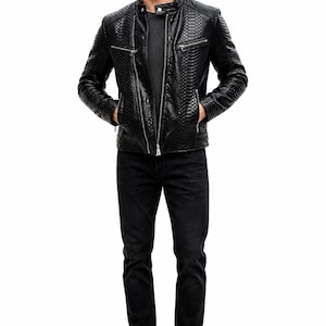 May include: A black leather jacket with a snakeskin texture, featuring a zip-up front and pockets. The jacket is paired with black jeans and black boots. The model is standing with hands in pockets.
