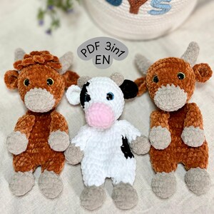 May include: Three crocheted cow toys. Two are brown with grey details, and one is white with black patches. Each has small horns, button eyes, and a soft, textured finish. The toys are designed to resemble Highland cattle. The text "PDF 3in1 EN" is visible.