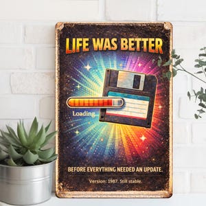 Pode incluir: Uma placa de metal em estilo vintage com o texto "LIFE WAS BETTER" em letras douradas. A placa apresenta um gráfico de disquete retrô com uma barra de carregamento, em um fundo colorido e radiante. O texto "BEFORE EVERYTHING NEEDED AN UPDATE" e "Version: 1987. Still stable." também estão incluídos.