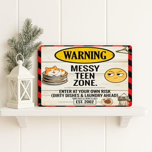 Puede incluir: Un letrero rectangular con fondo de madera y borde negro y rojo. El letrero dice "WARNING MESSY TEEN ZONE" con un gato y una cara enfadada. También dice "ENTER AT YOUR OWN RISK (DIRTY DISHES & LAUNDRY AHEAD) EST. 2002".