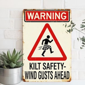 May include: A rectangular metal sign with a distressed finish. The sign features a red warning banner at the top and a red triangle with a running figure wearing a kilt. The text "KILT SAFETY - WIND GUSTS AHEAD" is below the triangle.