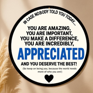 May include: Round sign with a black border and a cream-colored background. The sign features the text "IN CASE NOBODY TOLD YOU TODAY..." and inspirational messages in black and blue font. A black heart is at the bottom.