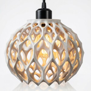Pu&ograve; includere: Lampada a sospensione sferica bianca con un design geometrico aperto. La lampada ha un attacco e un cavo neri. La lampadina &egrave; visibile attraverso il design aperto, emettendo una calda luce. La lampada &egrave; sospesa dal soffitto.