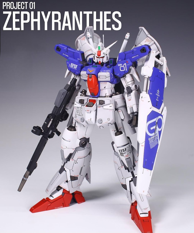 May include: A detailed model of a Zephyranthes robot, predominantly white with blue and red accents. The model features a large shield, a rifle, and the text "PROJECT 01 ZEPHYRANTHES" at the top. The robot has intricate mechanical details.