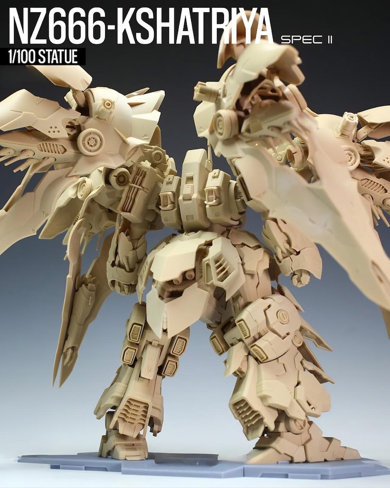 May include: A beige 1/100 scale statue of a detailed robot with large wing-like structures. The robot has intricate mechanical details and the text "NZ666-KSHATRIYA SPEC II" is visible at the top. The statue is on a gray surface.