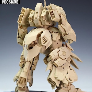 May include: A tan-colored, detailed statue of a robot, labeled "NZ666-KSHATRIYA SPEC II" and "1/100 STATUE". The robot has intricate mechanical designs, with visible panels, joints, and vents. It stands on a gray base, showcasing its complex structure.