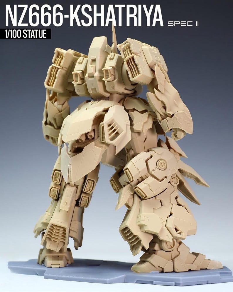 May include: A tan-colored, detailed statue of a robot, labeled "NZ666-KSHATRIYA SPEC II" and "1/100 STATUE". The robot has intricate mechanical designs, with visible panels, joints, and vents. It stands on a gray base, showcasing its complex structure.