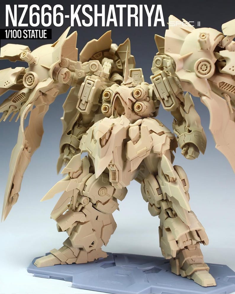 May include: A tan-colored 1/100 scale statue of a detailed robot, the NZ666-Kshatriya. The robot has large wing-like structures and intricate mechanical details. The statue is standing on a gray base. The text "NZ666-KSHATRIYA" and "1/100 STATUE" are visible.