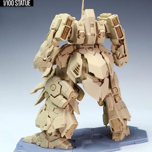 May include: A tan-colored, detailed statue of a robot, labeled "NZ666-KSHATRIYA SPEC II" and "1/100 STATUE". The robot is posed with its legs spread and arms bent, showcasing intricate mechanical designs and panels. It stands on a gray base.