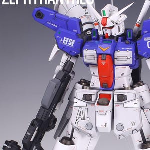May include: A detailed model of a Zephyranthes robot, predominantly white with blue and red accents. The robot features intricate mechanical details, including a large gun and the text "EFSF" on its shoulder. The text "PROJECT 01 ZEPHYRANTHES" is at the top.