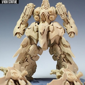 May include: A beige 1/100 scale statue of a robot, labeled "NZ666-KSHATRIYA SPEC II." The robot has detailed mechanical features, including articulated limbs, circular shoulder components, and sharp, wing-like structures extending from the legs.