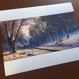 May include: A print of a winter landscape featuring a snow-covered road and trees. A figure on a red bicycle with a basket rides along the road. The artwork has a serene, naturalistic style with muted colors.