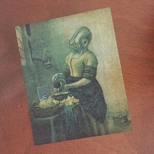 May include: A painting of a woman with a fish head pouring milk into a bowl. The woman is wearing a yellow blouse and a blue skirt. The painting is set in a kitchen with a wooden table and a window in the background.
