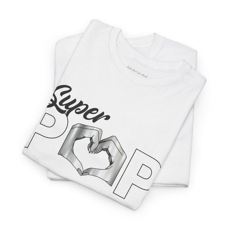 May include: White t-shirts with the words "Super Pop" in black script and outline letters. The letter "O" is replaced with a heart shape formed by two hands in a silver metallic color. The text "look don't get shook" is printed on the collar.