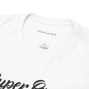 Peut inclure: Un t-shirt blanc &agrave; col rond. L'int&eacute;rieur du col pr&eacute;sente le texte imprim&eacute; "look don't get shook" dans une police cursive noire, suivi de la taille L, 100% coton, fabriqu&eacute; en R&eacute;publique dominicaine et quatre ic&ocirc;nes d'entretien textile.