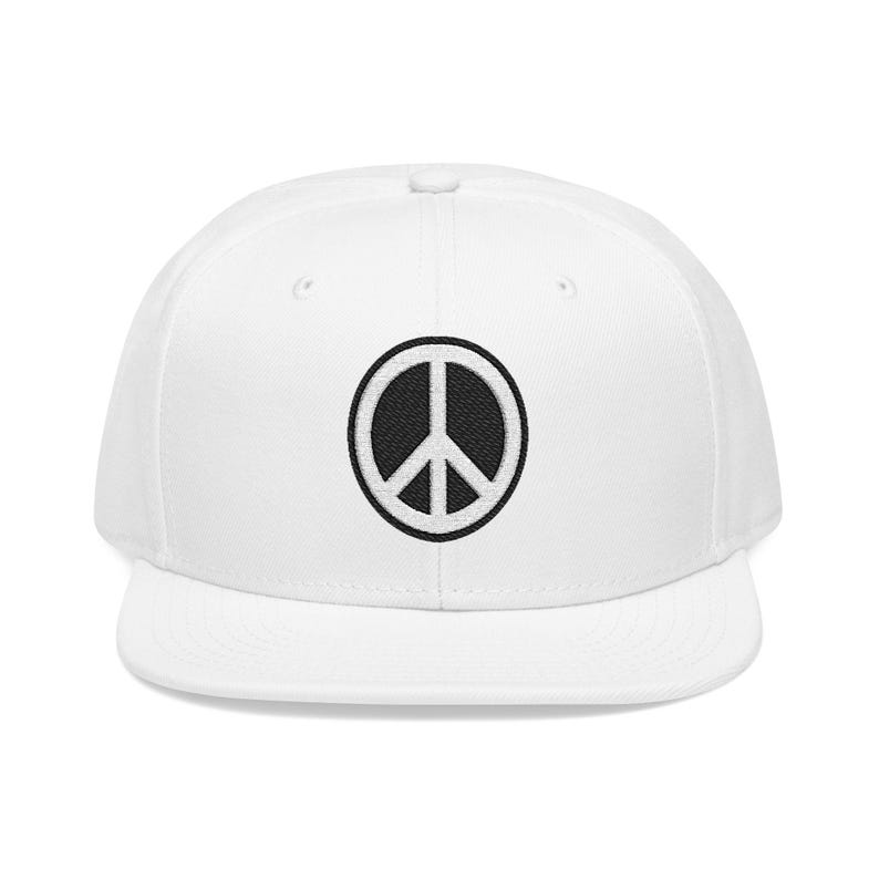May include: A white snapback cap featuring a circular black and white embroidered peace sign emblem centered on the front panel. The hat has a structured crown, a flat brim, and a button on the top, showcasing a clean and simple design.