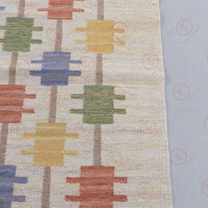 Detailed view of repeating Nordic geometric motifs on handwoven wool rug.
Scandinavian flat weave carpet with structured vertical alignment and earthy tones.
Modern cream area rug with mustard, blue, green, and rust color blocks.
Textured handmade wool rug for contemporary and minimalist interiors.
Geometric patterned Scandinavian rug with balanced and rhythmic design layout.