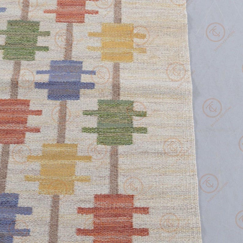 Detailed view of repeating Nordic geometric motifs on handwoven wool rug.
Scandinavian flat weave carpet with structured vertical alignment and earthy tones.
Modern cream area rug with mustard, blue, green, and rust color blocks.
Textured handmade wool rug for contemporary and minimalist interiors.
Geometric patterned Scandinavian rug with balanced and rhythmic design layout.