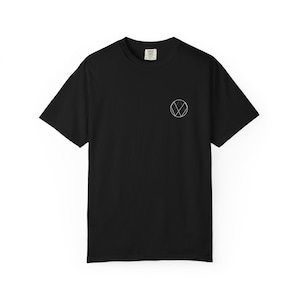 Pode incluir: T-shirt preto com um design geométrico branco no lado esquerdo do peito. A camisa de manga curta é feita de um material macio e é adequada para uso casual. A camisa tem gola redonda e uma etiqueta na parte de trás do pescoço.