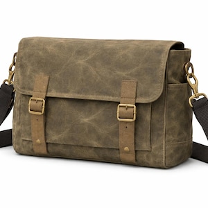 Può includere: Borsa messenger verde oliva con chiusura a patta e due cinturini con fibbia. La borsa ha una tracolla nera e hardware color ottone. La borsa è realizzata in tela cerata.