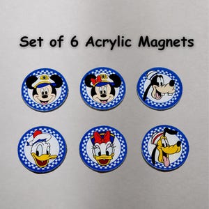 May include: A set of 6 round acrylic magnets featuring cartoon character faces including Mickey Mouse, Minnie Mouse, Goofy, Donald Duck, Daisy Duck, and Pluto. Each magnet has a blue and white checkered border. Text reads: Set of 6 Acrylic Magnets.
