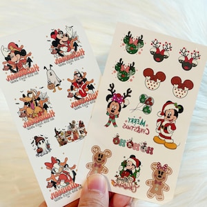 May include: Two sheets of adhesive stickers featuring Disney characters in Halloween and Christmas themes. The Halloween sheet displays ghosts, pumpkins, and costumed characters. The Christmas sheet includes reindeer ears, gingerbread figures, and holiday-themed Mickey and Minnie Mouse designs with text reading Merry Christmas and Ho Ho Ho.