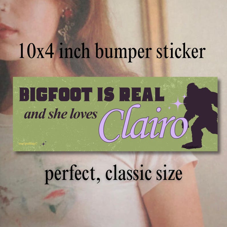 Może przedstawiać: Zielona naklejka na zderzak, ok. 25 x 10 cm, z napisem "BIGFOOT IS REAL and she loves Clairo." Sylwetka Bigfoota znajduje się po prawej stronie. Naklejka ma estetykę vintage.