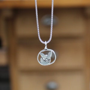 May include: A silver necklace with a round pendant featuring a stylized image of a fox's head.