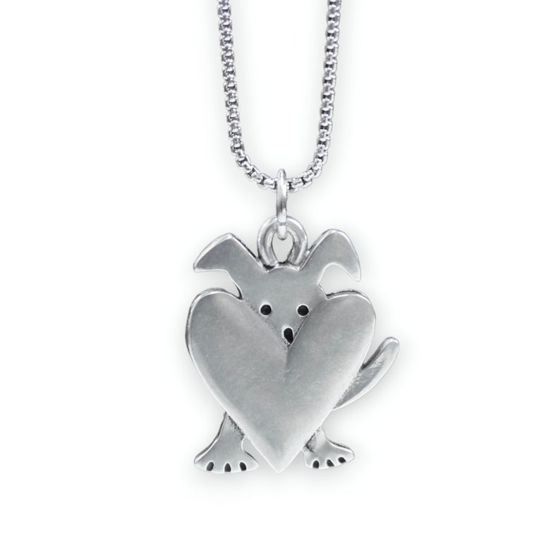 May include: Silver necklace with a charm of a dog holding a heart in its paws.