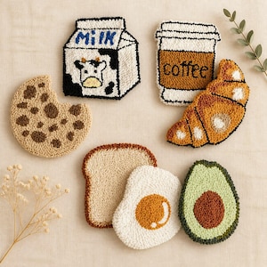 Peut inclure: Ensemble de dessous de verre faits à la main sur le thème de l'alimentation. L'ensemble comprend un carton de lait, une tasse de café, un croissant, un biscuit, une tranche de pain, un œuf au plat et un avocat. Chaque dessous de verre est coloré.
