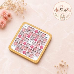 Pu&ograve; includere: Un sottobicchiere quadrato con cornice in legno chiaro caratterizzato da un motivo a mosaico di piastrelle quadrate rosa, piastrelle argentate glitterate, stelle rosa e gemme trasparenti. Il logo ArtShopSis &egrave; visibile nell'angolo in alto a destra.
