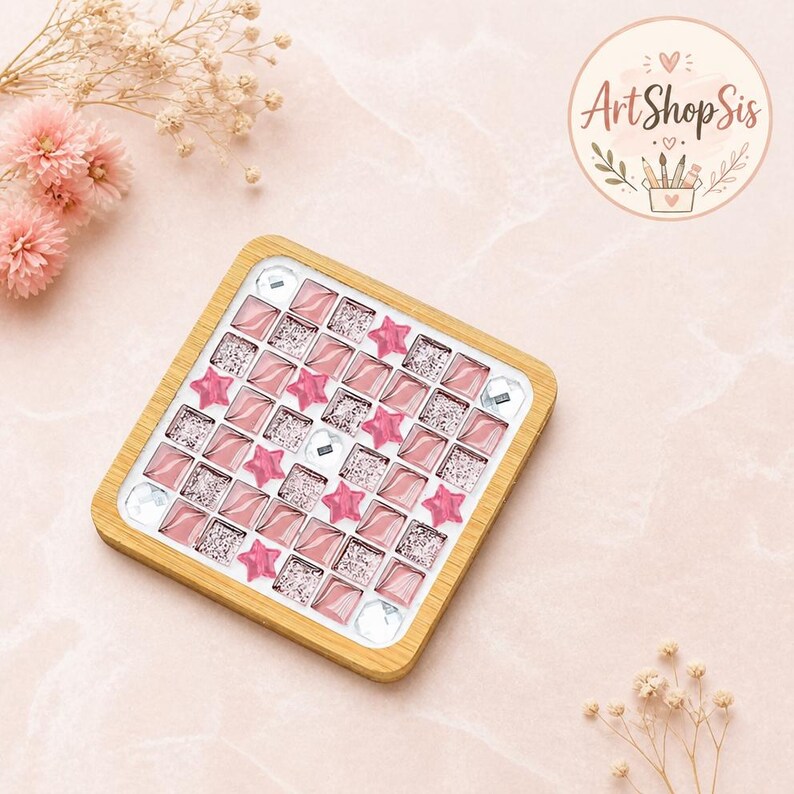 Pu&ograve; includere: Un sottobicchiere quadrato con cornice in legno chiaro caratterizzato da un motivo a mosaico di piastrelle quadrate rosa, piastrelle argentate glitterate, stelle rosa e gemme trasparenti. Il logo ArtShopSis &egrave; visibile nell'angolo in alto a destra.