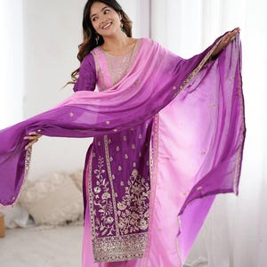 May include: A purple and pink salwar kameez, a traditional South Asian outfit. The kurta and palazzo trousers are adorned with gold embroidery. A matching dupatta, with a colour gradient, adds a flowing element. The outfit is suitable for festive occasions and celebrations.