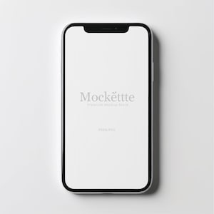 Könnte beinhalten: Ein Smartphone mit schwarzem Rahmen und weißem Bildschirm. Auf dem Bildschirm steht in hellgrauer Schrift "Mockettte Premium Mockup Store". Am unteren Bildschirmrand steht "PSD & JPEG".