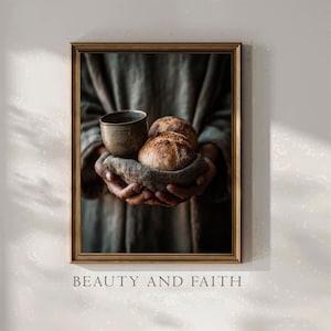 Può includere: Stampa incorniciata raffigurante una persona che tiene una tazza di ceramica e due pagnotte in un panno. L'immagine ha una calda tavolozza di colori neutri. Il testo "BEAUTY AND FAITH" è stampato in basso.