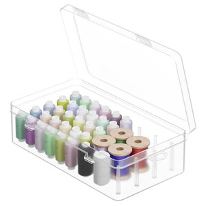 May include: A clear plastic storage box filled with colorful sewing thread spools and small bottles of paint. The box is open, revealing a variety of colors, including green, purple, yellow, and blue. Several wooden spools are also visible.