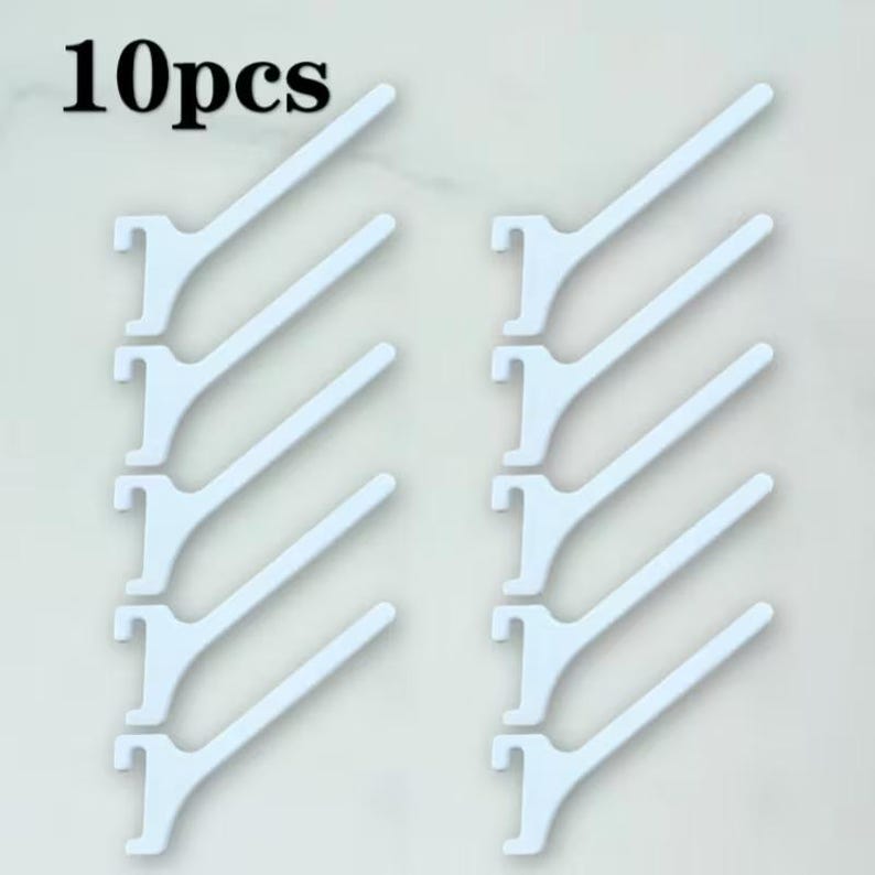 Op de afbeelding: Een set van 10 witte plastic displayhaken gerangschikt in twee verticale kolommen van vijf. Elke haak heeft een platte, schuine arm die uitsteekt vanaf een inkeping-montagebasis voor bevestiging aan een wanddisplay.