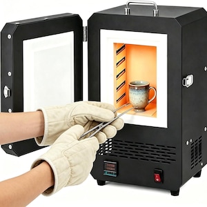 Pode incluir: Um forno elétrico preto com a porta aberta revelando uma câmara interna laranja brilhante. Uma caneca de cerâmica está sendo colocada dentro do forno usando pinças de metal. A unidade possui um display digital e um interruptor vermelho.
