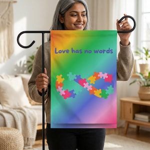 May include: A garden flag with a rainbow gradient background. The flag features a colorful infinity symbol made of puzzle pieces and the text "Love has no words" in purple.