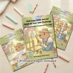 Op de afbeelding: Een set van drie afdrukbare journals met capibara-illustraties. De journals bevatten titels als "My Simple Plan" en "My Challenge Tracker". De tekst luidt "Chill Capy Goals Journal Week 10: Your Solo Challenge". Er liggen kleurpotloden verspreid rond de journals.