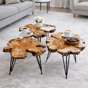 Peut inclure: Trois tables basses en bois aux formes naturelles et irrégulières, de couleur marron clair. Chaque table est soutenue par des pieds en épingle à cheveux en métal noir. Une table présente une tasse de café et une petite assiette avec une pâtisserie.