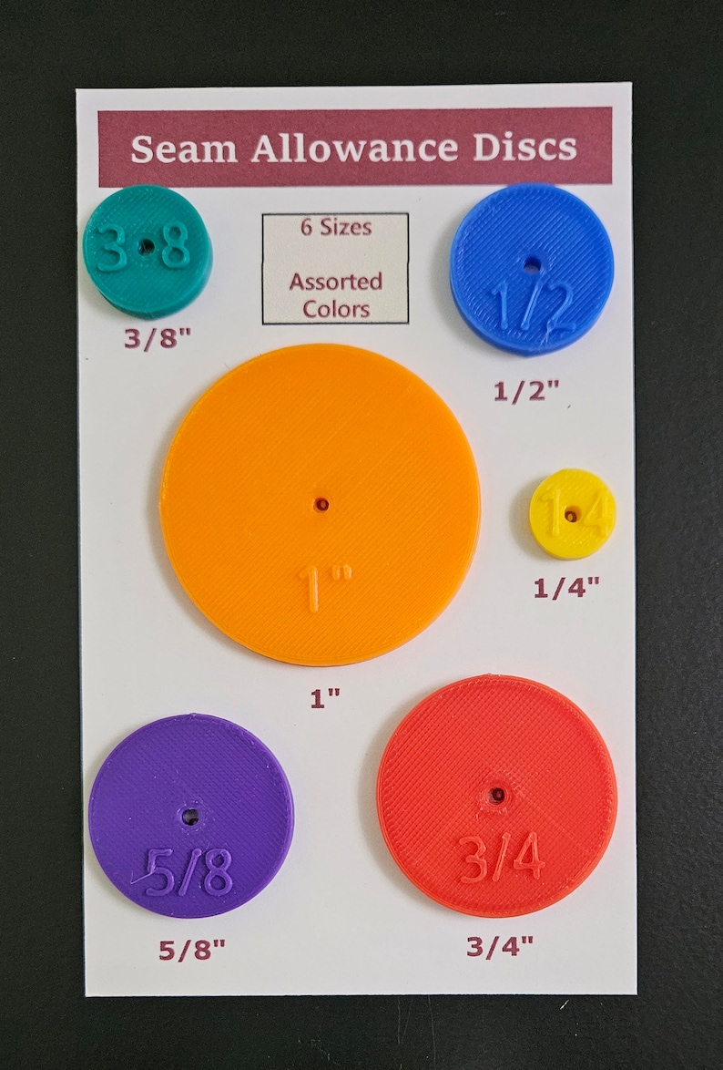 May include: Six colorful plastic discs with different seam allowances, including 3/8 inch, 1/2 inch, 1 inch, 1/4 inch, 5/8 inch, and 3/4 inch. The discs are labeled with their respective sizes. The text "Seam Allowance Discs" and "6 Sizes Assorted Colors" is printed on the white card.