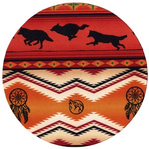 May include: A round fabric coaster with a Native American design. The coaster features a red, orange, and white geometric pattern with black accents. Three black wolf silhouettes are running across the top of the coaster. Two dreamcatchers are on the bottom of the coaster.