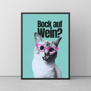 Könnte beinhalten: Gerahmtes Poster mit einer Katze, die eine rosa Brille trägt und die Zunge herausstreckt. Die Katze befindet sich vor einem türkisfarbenen Hintergrund mit dem deutschen Text "Bock auf Wein?" in Schwarz.