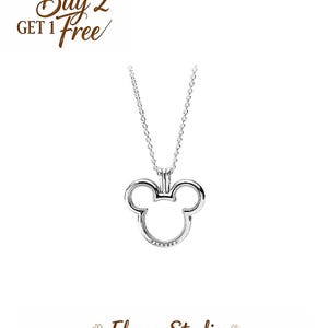 Op de afbeelding: Een zilverkleurige ketting met een Mickey Mouse-hoofd hanger. De hanger is een holle omtrek van het gezicht van het iconische personage. De ketting heeft een fijne ketting en de merknaam is zichtbaar op de hanger. De tekst "Buy 2 Get 1 Free" is ook aanwezig.