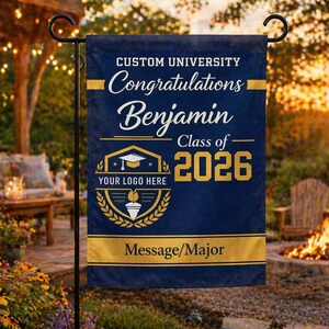 Peut inclure: Un drapeau de jardin de graduation bleu marine avec des accents dorés. Le drapeau indique "Custom University Félicitations Benjamin Classe de 2026" avec un espace pour un logo et une spécialité. Le drapeau est suspendu à l'extérieur.