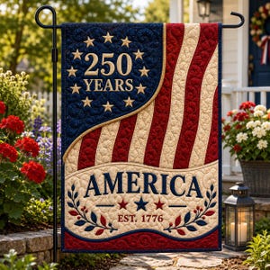 May include: A rectangular garden flag featuring a quilted American flag design with wavy red and cream stripes. The blue canton displays eleven gold stars surrounding the text 250 YEARS. Below, the word AMERICA sits above EST. 1776 and floral sprigs.