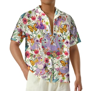 May include: Short-sleeved button-down shirt with a whimsical floral and character print. The design features purple dragons, butterflies, and flowers in shades of pink, orange, and green on a cream background.