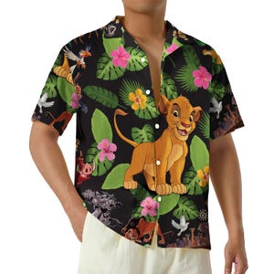 May include: Short-sleeved button-down shirt featuring a black background with a colorful print of Simba from The Lion King, tropical leaves, and flowers. The shirt has a classic collar and a relaxed fit.