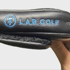 以下が含まれることがあります： 黒い持ち手と「But First, Coffee」のテキストが黒い太字でプリントされた白いセラミックマグ。マグカップはぼやけた背景に置かれており、居心地の良い環境を示唆しています。